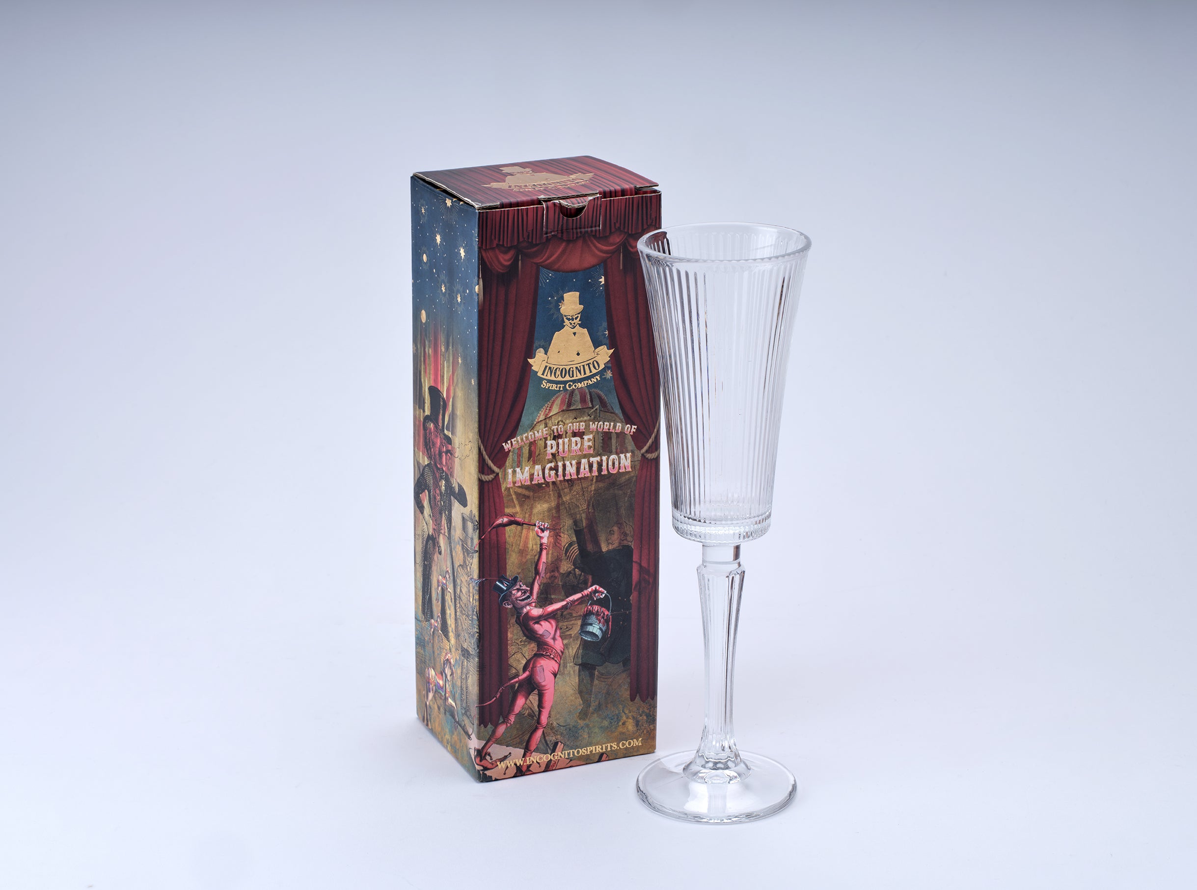 A clear ribbed glass goblet or flute-shaped drinking glass standing beside its illustrated product box on a light gray studio background.