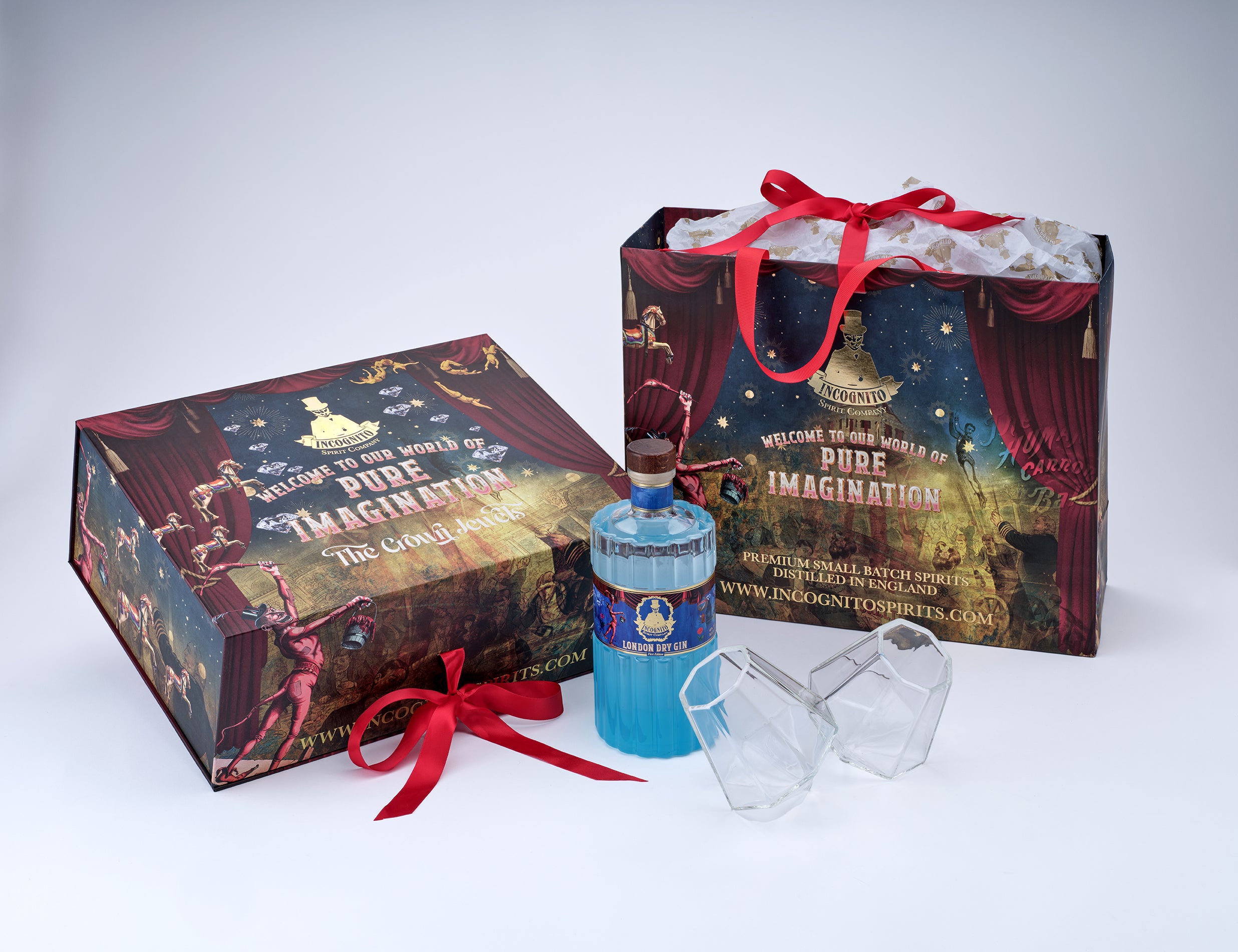 A Magic Kingdom themed gift set featuring a bottle of blue Vodka with a blue label, two clear plastic cups, and two decorative boxes with red ribbons. The boxes are printed with 'WELCOME TO THE WORLD OF DISNEY'S PURE IMAGINATION - THE CHARades' in a theatrical curtain-style design.