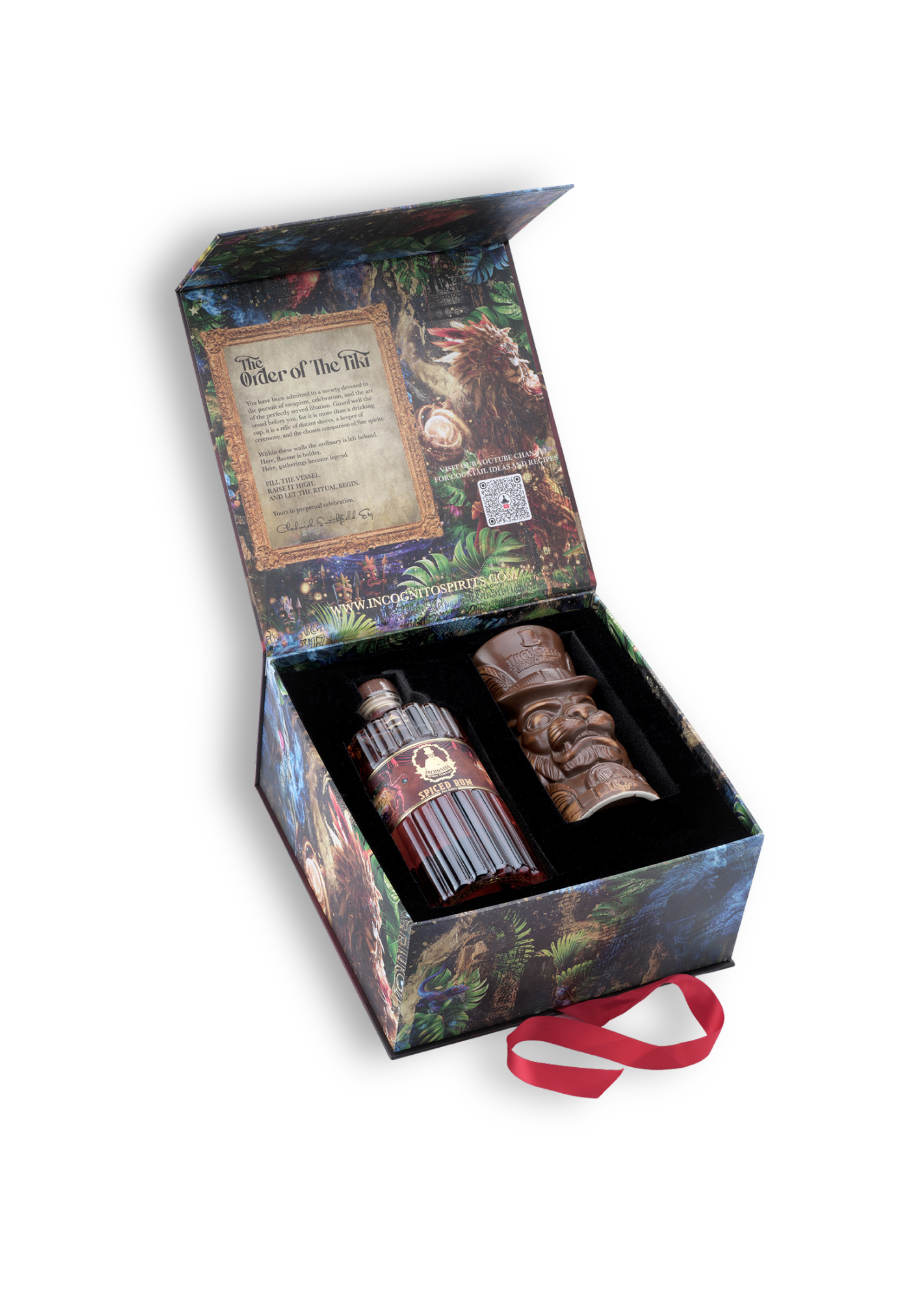 A boxed gift set on a white background, featuring an open illustrated box with a parchment insert and two dark carved items inside, including a tiki-style figure and a bottle or canister with a red label. A red ribbon is placed in front of the box.