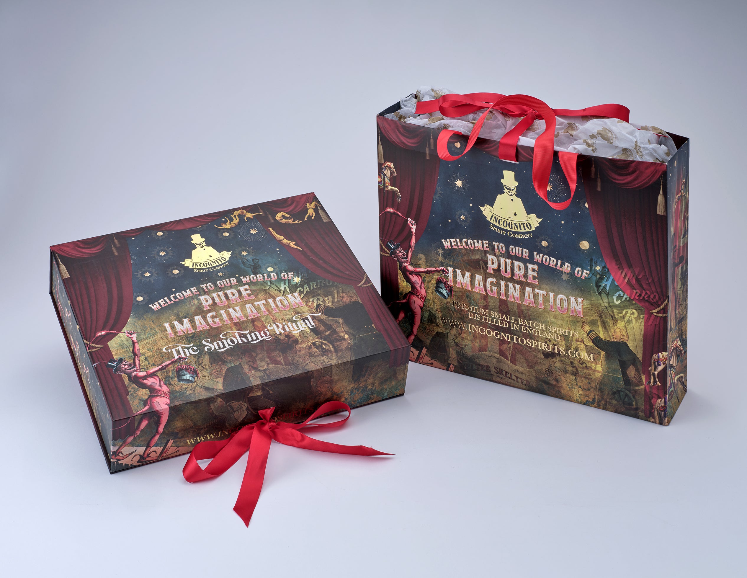 A branded gift box and matching gift bag with red ribbon handles, printed with theatrical curtains, stage lighting, and the text 'Welcome to our world of Pure Imagination' and 'The Wizard of Oz.'.